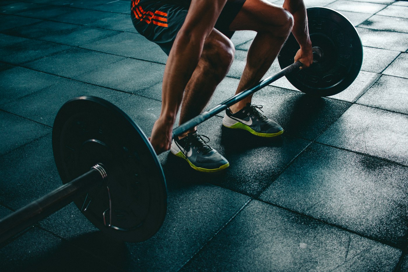 A person lifting a barbell in a gym, cropped above the shoulders